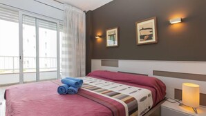 Una habitación de hotel con una cama, una mesita de noche, una lámpara y dos cuadros colgados en la pared.