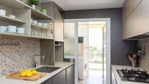 Una cocina moderna con una isla central, estufa integrada y vistas a un balcón.