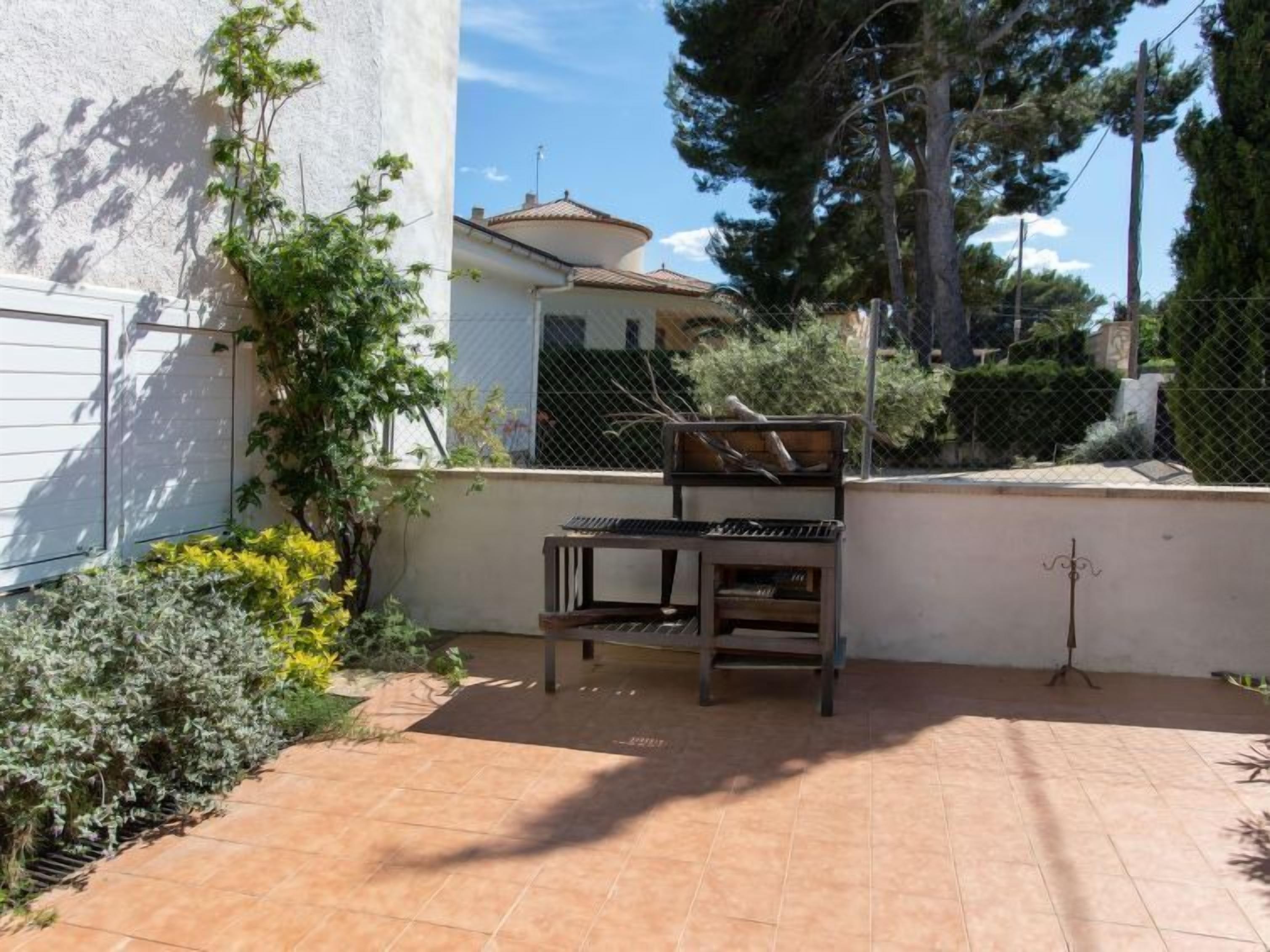 A patio area with a wooden bench, a small table, and a decorative metal stand.