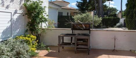 A patio area with a wooden bench, a small table, and a decorative metal stand.