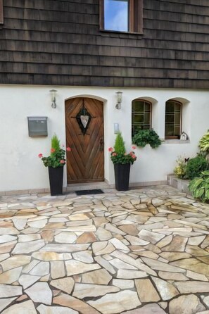 Stunning entrance with a diamond-shaped window and potted plants.
