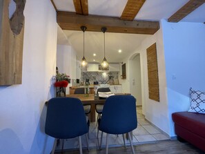Enjoy meals in this cozy dining area with a wooden ceiling, modern kitchen, and comfortable seating for two.