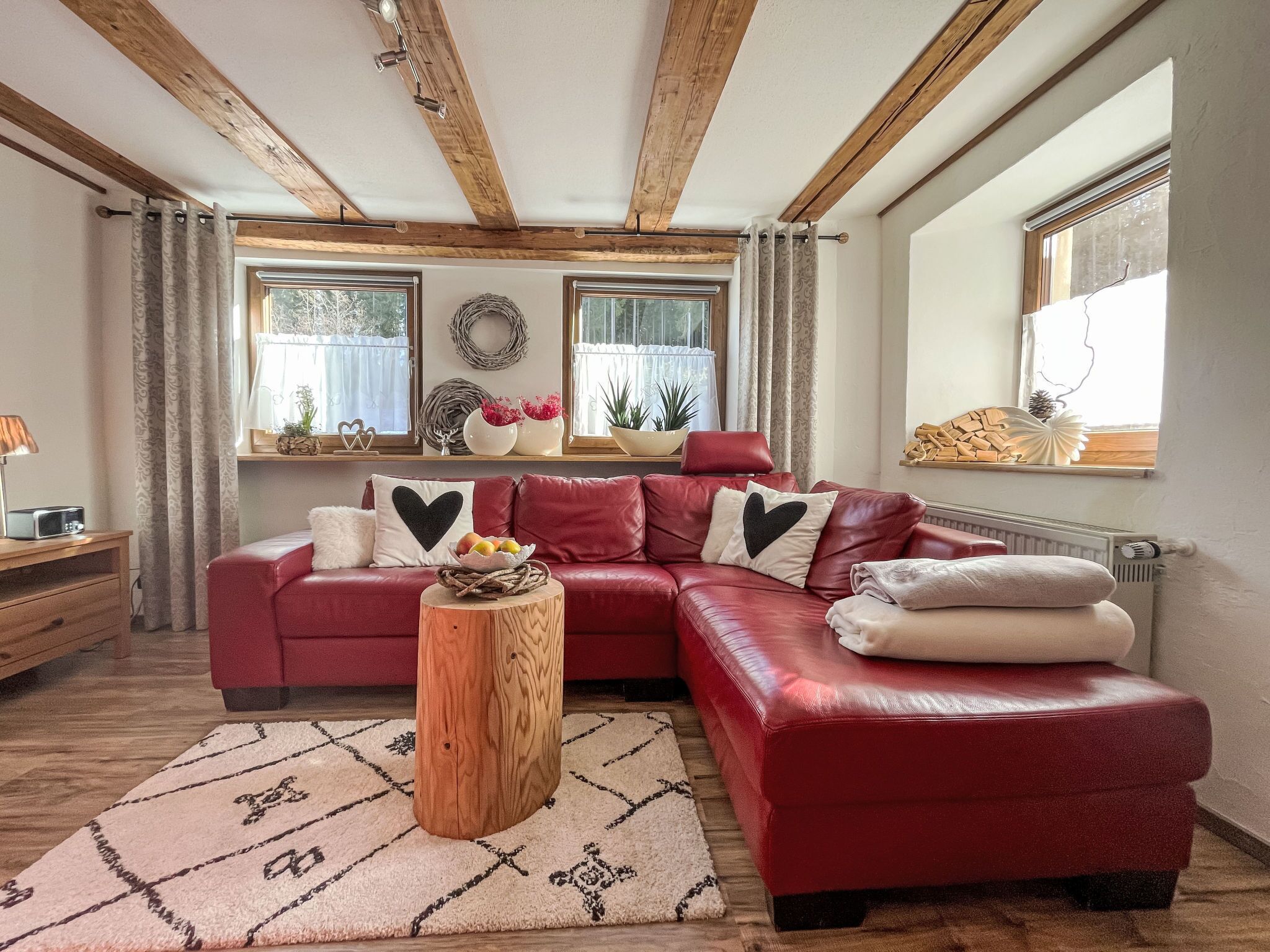A cozy living room with a red leather sofa, a wooden coffee table, and a patterned rug.