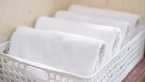 A white plastic basket with a perforated design, containing rolled white towels. - Gyeongju Jang (Gyeongju)