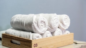A wooden box with three rolled white towels.