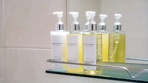 A bathroom shelf with three bottles of Arder Premium products: conditioner, shampoo, and body wash.