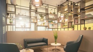 Un interior moderno con un sofá, dos sillones, una mesita y un estante con plantas.