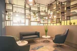 Un interior moderno con un sofá, dos sillones, una mesita y un estante con plantas.