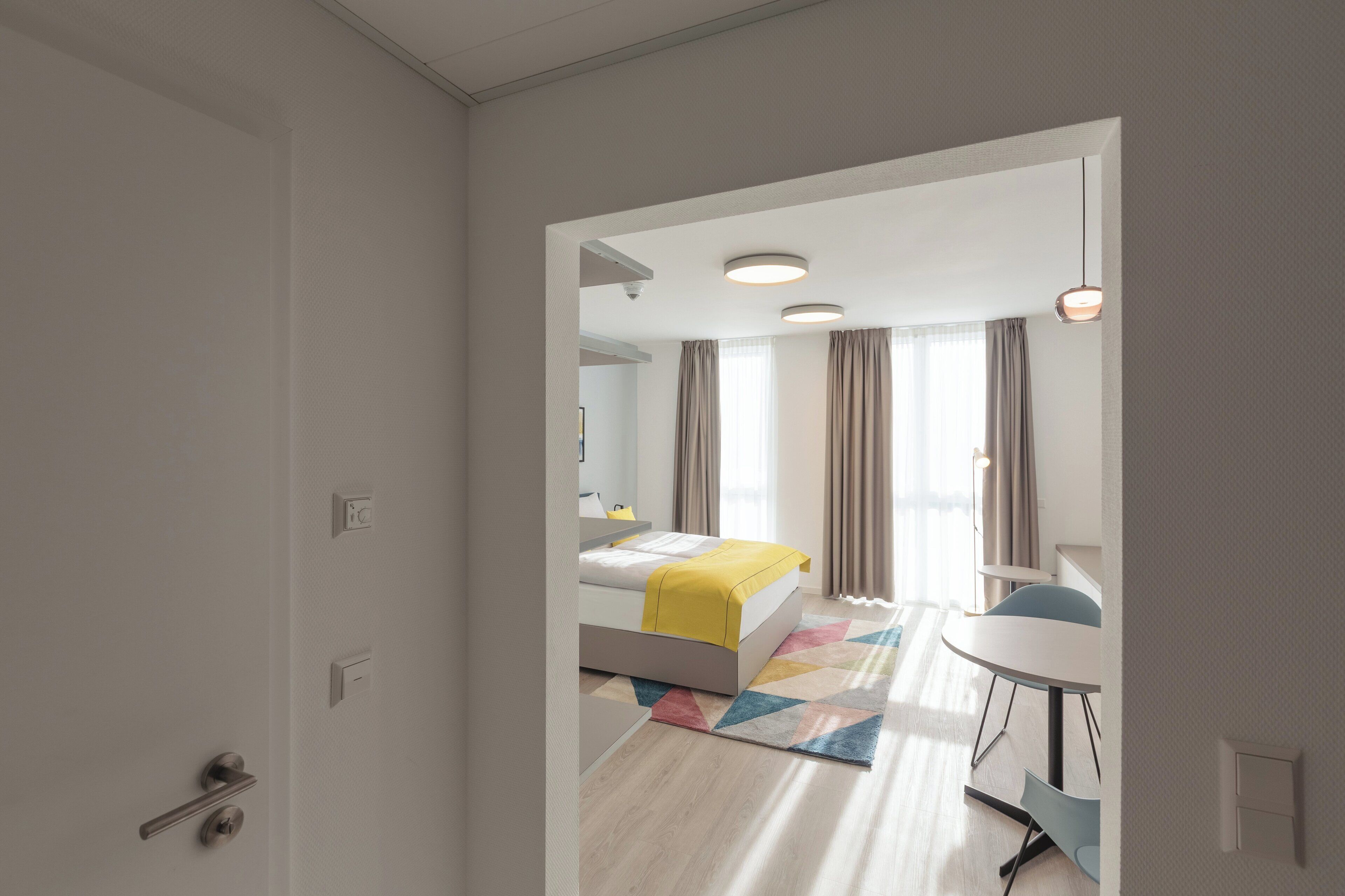Una habitación de hotel moderna con una cama, un escritorio y una silla.