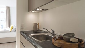 Una cocina moderna con un lavamanos de acero inoxidable, una bandeja de madera con cuencos y una ventana con cortinas.