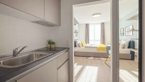 Una cocina moderna con un lavamanos de acero inoxidable y una zona de comedor con un sofá y una mesa.