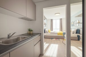 Una cocina moderna con un lavamanos de acero inoxidable y una zona de comedor con un sofá y una mesa.