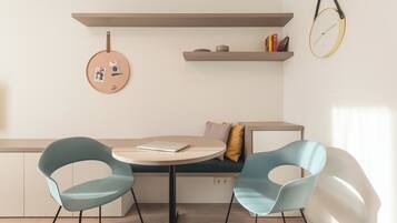 Une pièce moderne avec une table ronde, deux chaises, un banc et une horloge fixée au mur.