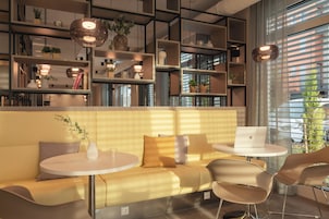 Un área de estar moderna con un sofá, mesas redondas y estantes decorados con objetos decorativos.