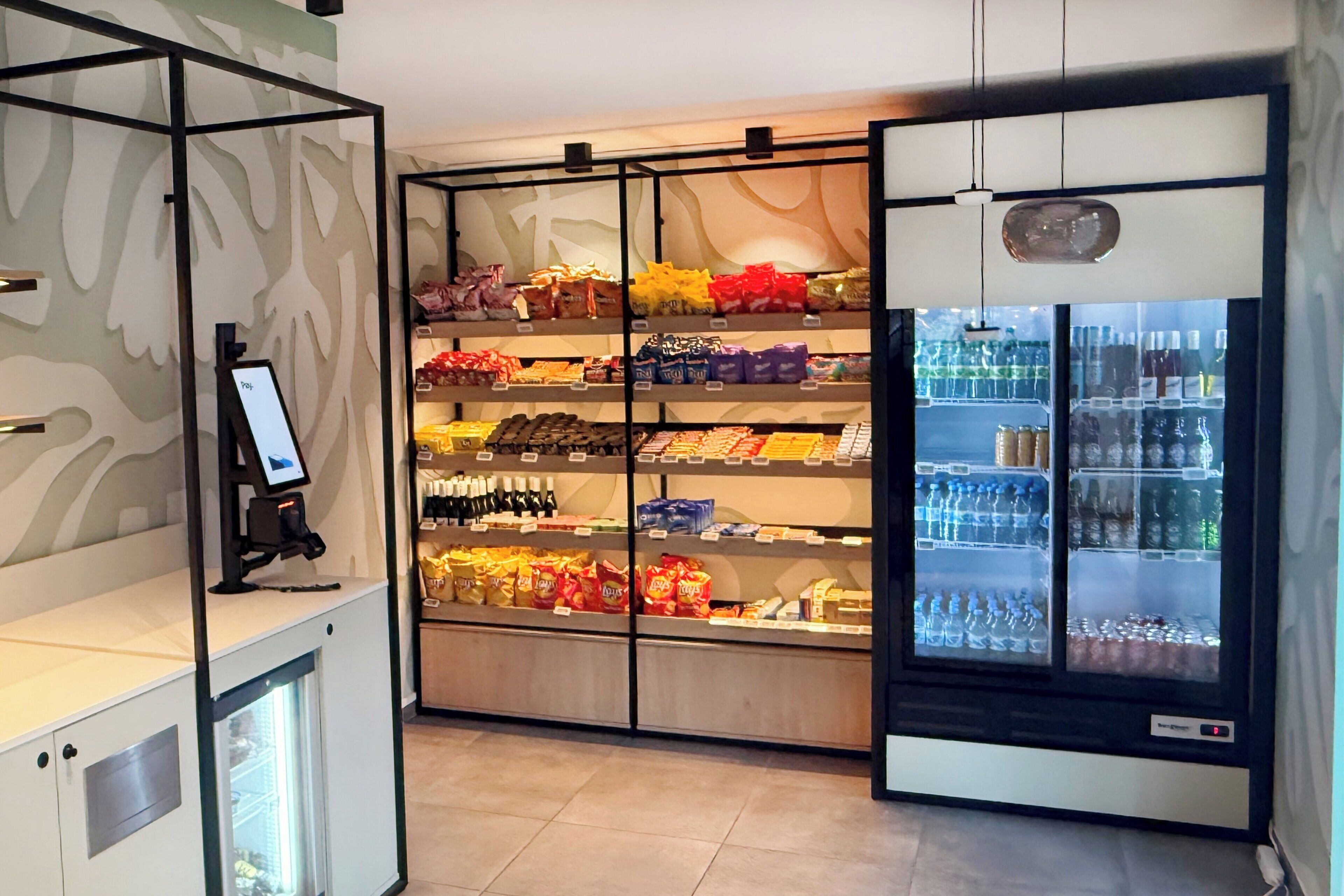 A self-service snack and beverage kiosk with multiple shelves of snacks and a refrigerated section with bottled water and other beverages.