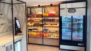 Un distributeur automatique proposant des collations et des boissons en libre-service, avec plusieurs étagères remplies de collations et un compartiment réfrigéré contenant des bouteilles d’eau et d’autres boissons.