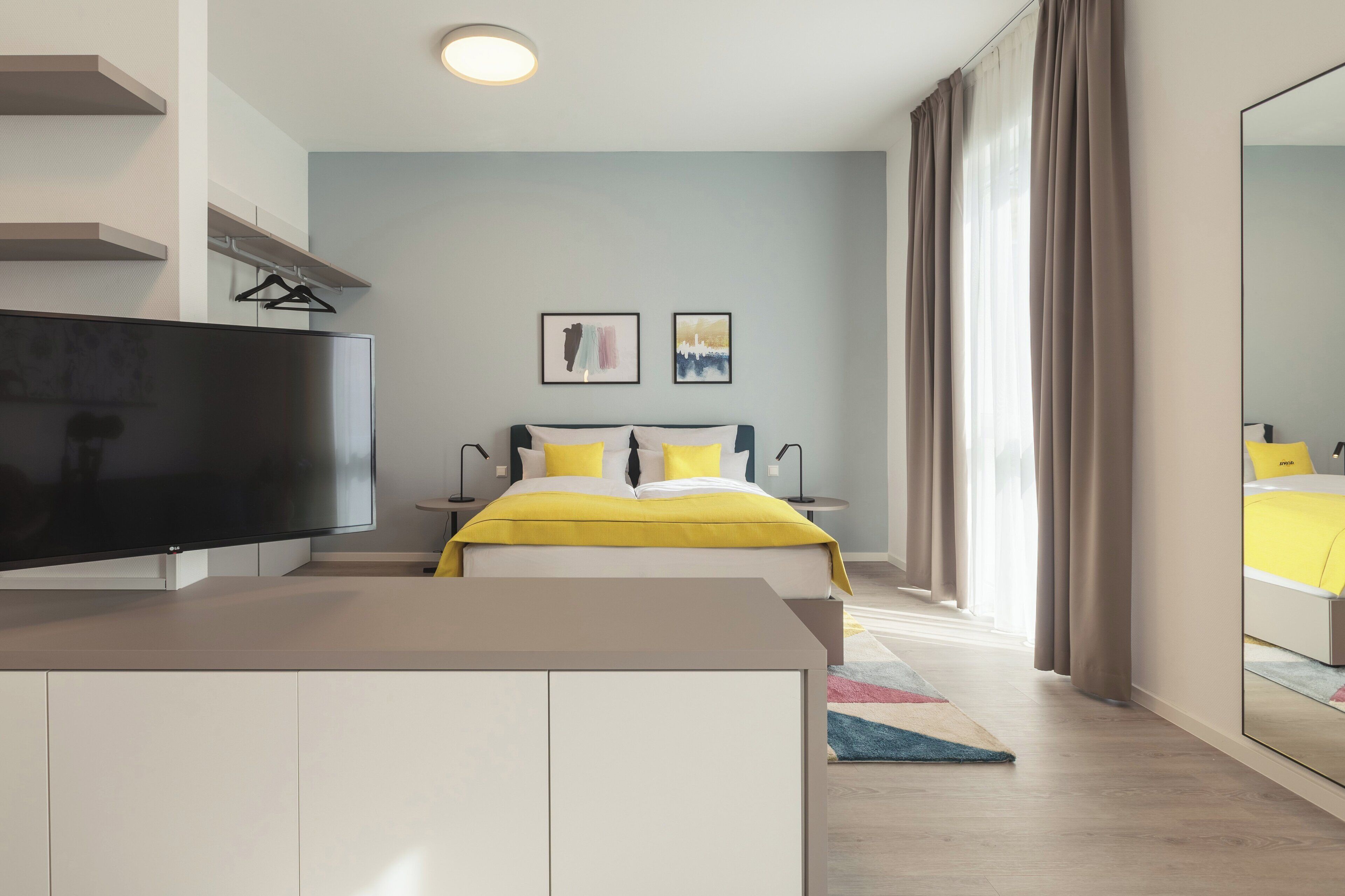 Une chambre à coucher moderne avec un lit, un téléviseur à écran plat et des œuvres d’art accrochées au mur.