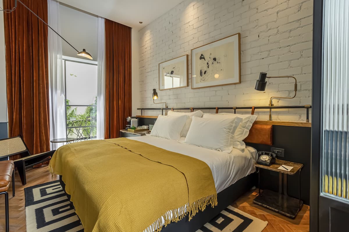 Een moderne slaapkamer met een groot bed, een tafeltje, een nachtkastje en een raam met gordijnen.