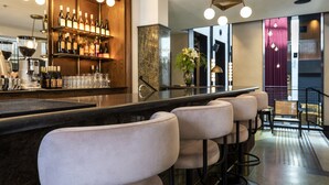 Uma área de bar com um balcão comprido, vários bancos e uma estante para vinhos com garrafas.