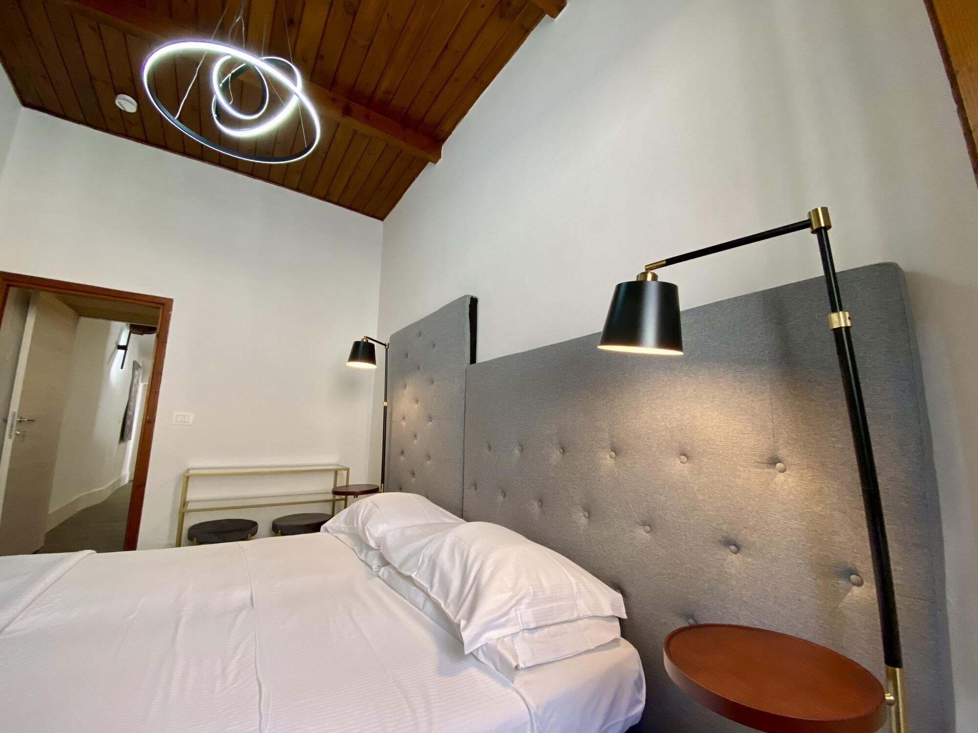 Een slaapkamer met een bed, een hoofdeinde, een nachtkastje en een vloerlamp.