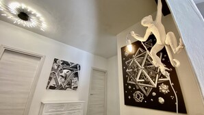 A room with a modern ceiling light fixture, a black and white abstract painting, and a white decorative sculpture. - Appartamento Ginori (Florence)