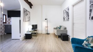 A modern living room with a grey sofa, a blue armchair, a floor lamp, and artwork on the walls. - Appartamento Ginori (Florence)