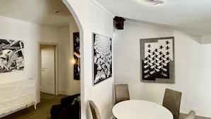 A dining area with a round table and four chairs, a white wall with two black and white artwork, and a white ceiling with a light fixture. - Appartamento Ginori (Florence)