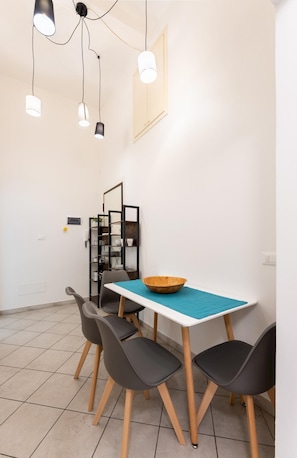 Uma sala de jantar com mesa, cadeiras e luminárias pendentes.