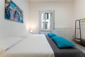 A bedroom with a bed, a dresser, a radiator, and a window with shutters. - Appartamento Zanobi (Florence)