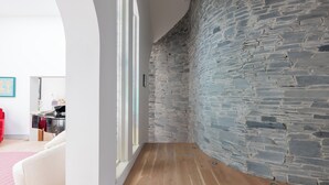 Un interior moderno con pared de piedra, suelo de madera y una silla roja.