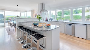 Una cocina moderna con una isla central, electrodomésticos de acero inoxidable y ventanas amplias que ofrecen vistas al exterior.