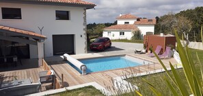 Ein Wohnhaus mit Swimmingpool, einer überdachten Terrasse und einem roten Auto auf der Auffahrt.
