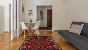 A living room with a sofa, a patterned rug, and a dining area with chairs and a table. - ★ Bright & Spacious 2-bedroom Apartment in Athens (Athens)
