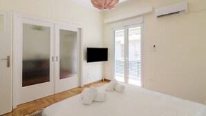 A bedroom with a bed, a television, a sliding glass door, and an air conditioning unit. - ★ Bright & Spacious 2-bedroom Apartment in Athens (Athens)