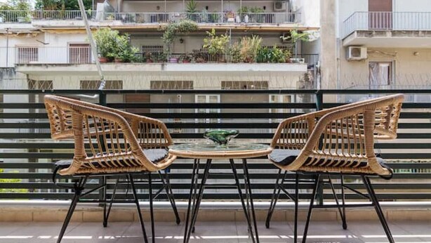 A balcony with wicker chairs and a small table, overlooking a residential area with balconies and plants. - ★ Bright & Spacious 2-bedroom Apartment in Athens (Athens)