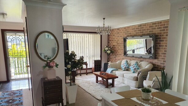A living room with a sofa, coffee table, dining table, and chairs. There is a mirror on the wall, a chandelier, and a fireplace. - The Junction Estate. Cool, Calm and Cozy. (Wallerawang)