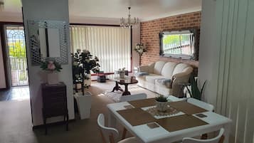 A dining area with a white table and chairs, a sofa, and a potted plant.