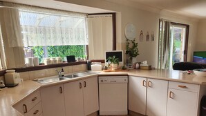 A modern kitchen with a dishwasher, a sink, and a window with sheer curtains. - The Junction Estate. Cool, Calm and Cozy. (Wallerawang)
