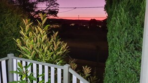 A porch with a railing, a view of a sunset, and a hedge. - The Junction Estate. Cool, Calm and Cozy. (Wallerawang)