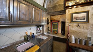 A kitchen with wooden cabinets, a granite countertop, and a tiled backsplash. - Kadievi (Ürgüp)