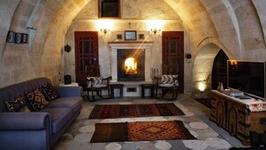 A cozy living room with a fireplace, stone walls, and a sofa. - Kadievi (Ürgüp)