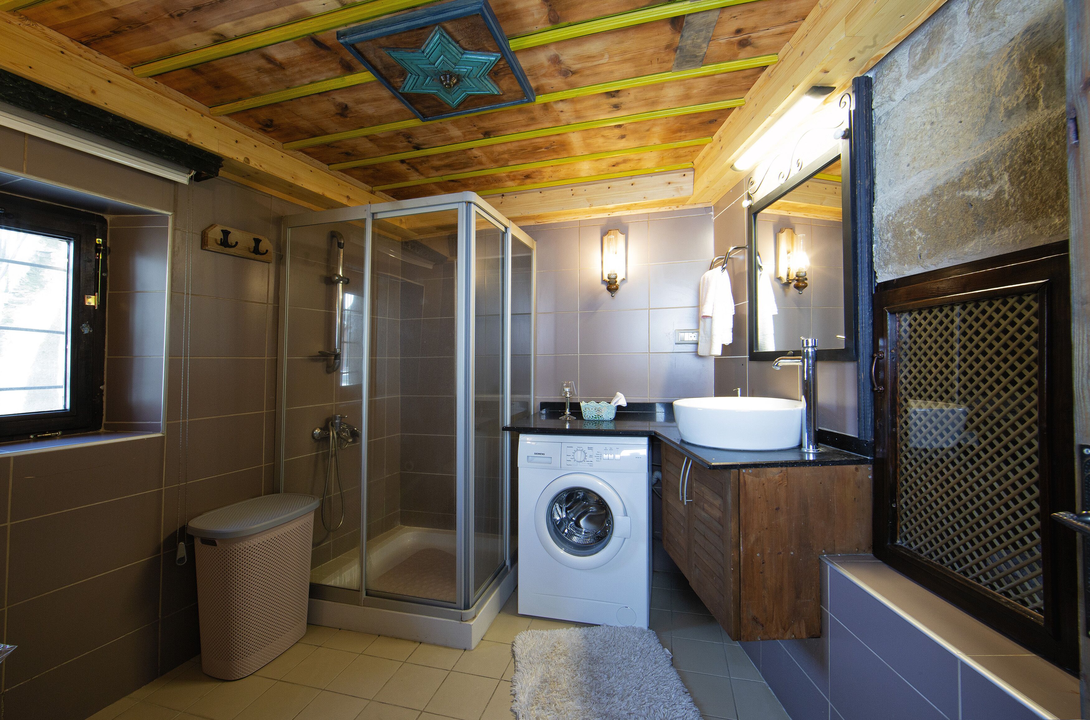 A modern bathroom with a glass shower enclosure, a built-in washing machine, and a large sink.