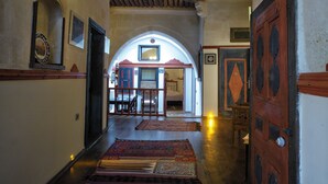 A hallway with wooden floors, a wooden door, and a small table with chairs. - Kadievi (Ürgüp)