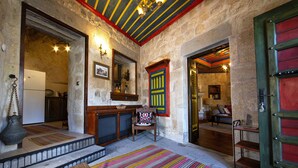 A rustic interior with a wooden staircase, a colorful striped rug, and a traditional door with vibrant colors. - Kadievi (Ürgüp)