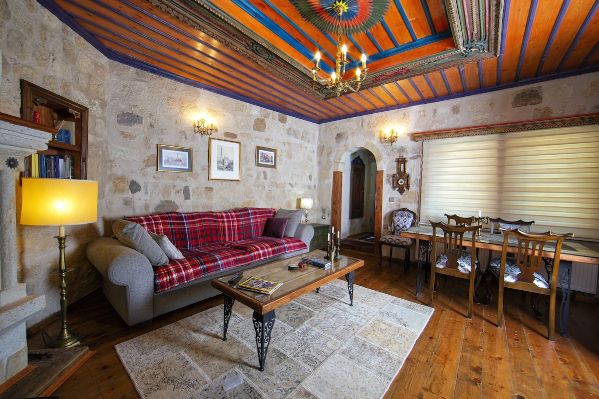 A cozy living room with a red plaid sofa, wooden coffee table, and a fireplace.