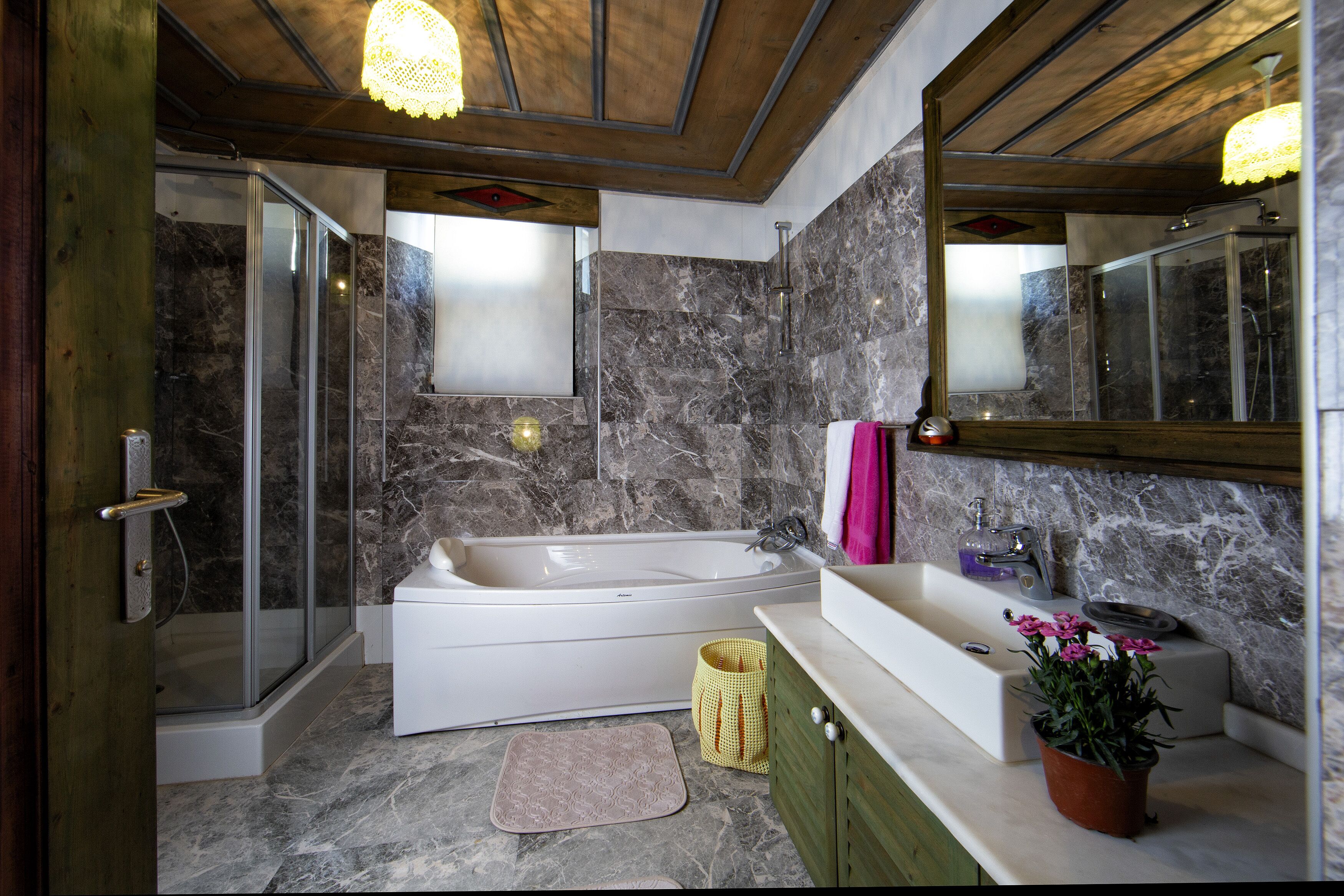 A modern bathroom with a glass shower enclosure, a freestanding bathtub, and a vanity with a sink and mirror.
