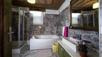 A modern bathroom with a glass shower enclosure, a freestanding bathtub, and a vanity with a sink and mirror.