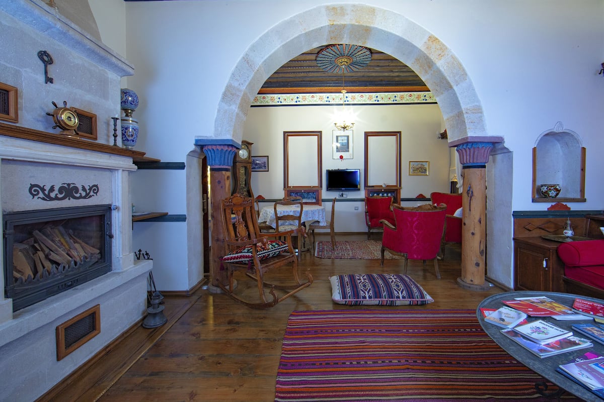 A traditional living room with a fireplace, wooden furniture, and a red sofa.