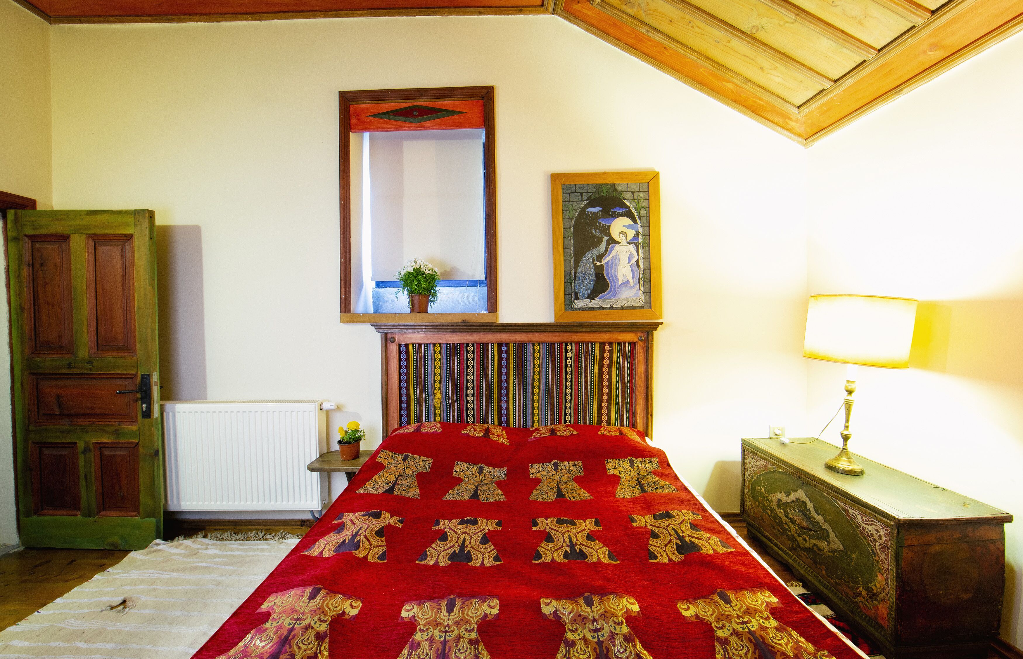 Un dormitorio con cama, cabecero de madera, espejo, lámpara y cómoda.