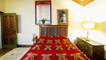 Un dormitorio con cama, cabecero de madera, espejo, lámpara y cómoda.